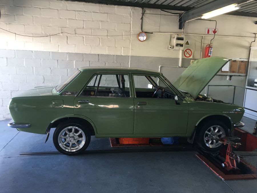 Green classic Datsun on the workshop lift
