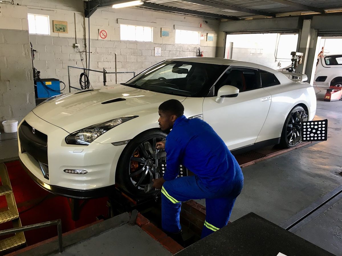 Technician fitting alignment clamps to a Nissan GT-R