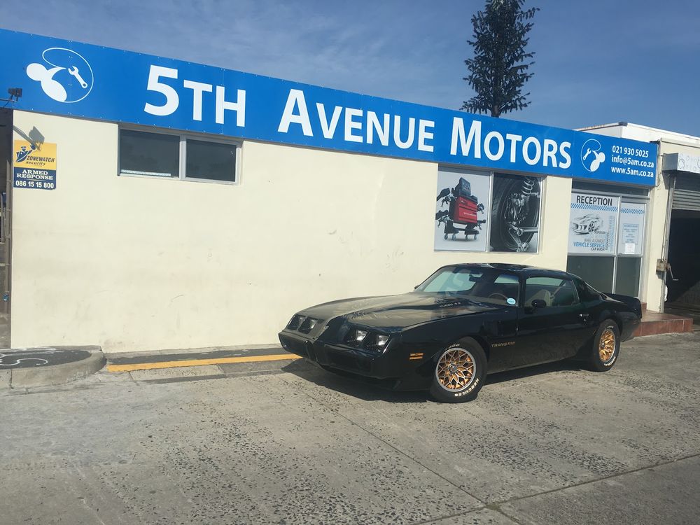 5th Avenue Motors building with a black Pontiac Trans Am